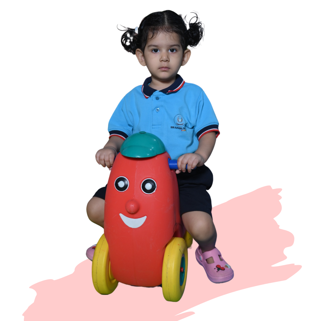 Child in BrainBunny Juniors uniform on a toy car.